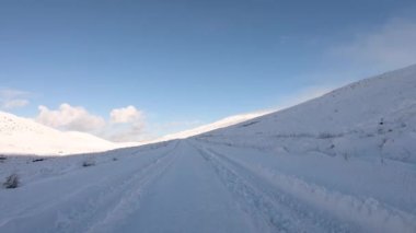 Driving through the snow covered Glenveagh National Park in the shadow of a mountain - County Donegal. Republic of Ireland.