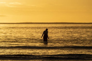 İrlanda 'da Atlantik Okyanusu' na giden kadın yüzücü silueti.