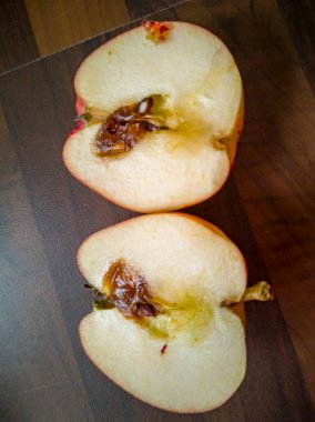 Sliced rotten apple on kitchen worktop. clipart