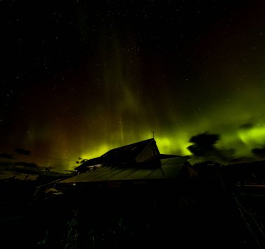 The Aurora Borealis, the northern lights, showing up above bungalow in County Donegal, Ireland. clipart