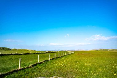 Coastal rural field in Ireland with fence on a sunny day. clipart