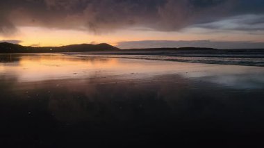 Donegal, İrlanda 'daki Portnoo Narin plajında gün batımında kumsala yağmur yağıyor..