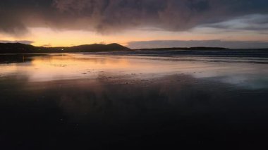 Donegal, İrlanda 'daki Portnoo Narin plajında gün batımında kumsala yağmur yağıyor..