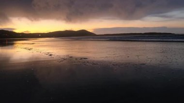Donegal, İrlanda 'daki Portnoo Narin plajında gün batımında kumsala yağmur yağıyor..