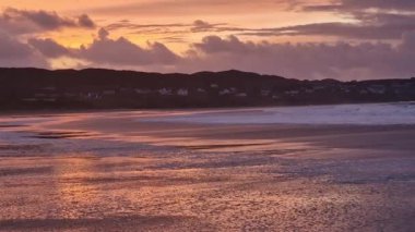 Donegal, İrlanda 'daki Portnoo Narin plajında gün batımında kumsala yağmur yağıyor..