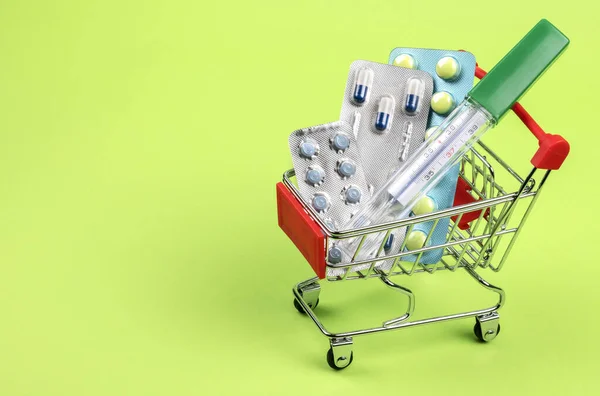 Termometre Haplar Tabletler Vitaminler Yeşil Arka Plandaki Alışveriş Arabasında Konsept — Stok fotoğraf