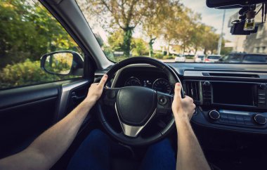 Erkek sürücü ellerini direksiyona, şoför arabasını da caddeye yakın tut.