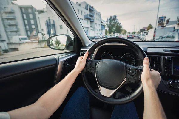 stock image Man driving his new car stands in front of the steering wheel, confident driver on the city streets