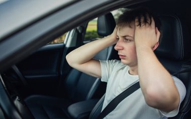 Stressed and bewildered driver, pissed off keeps hands to head, has traffic problems. Unlucky man has a road accident