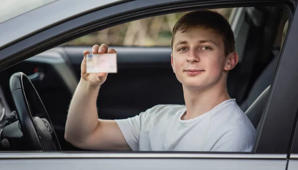 Guy shows the driver license out of the car window