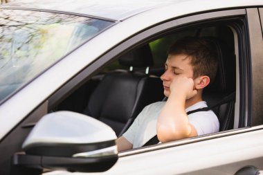 Trafik sıkışıklığında iş çıkışı trafikte beklerken neredeyse uyuyan genç sürücü yoruldu. Yorgun genç adam dinlenmek için arabasını kullanmayı bırak..