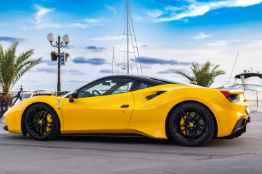 Sarı spor araba Ferrari Spider yat limanında gün batımında