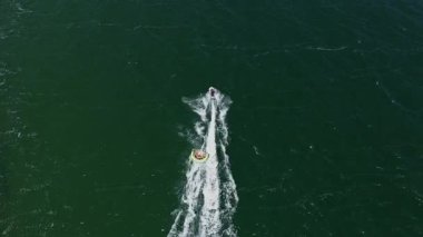 Jet ski şişme su aracını çekiyor. Kumsaldaki turistler için deniz eğlencesi. Bulgaristan 'ın Karadeniz kıyısındaki güneşli plajı