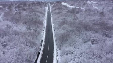 Kışın kardan temizlenmiş bir dağ yoluna açılan hava manzarası. Kış manzarası