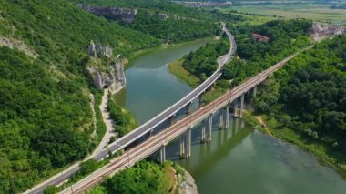 Dağdaki bir barajın üzerinden geçen bir yol ve demiryolu manzarası