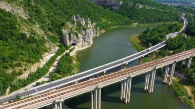 Dağdaki bir barajın üzerinden geçen bir yol ve demiryolu manzarası