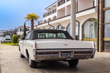 Marina Dinevi, Sveti Vlas, Burgaz, Bulgaristan - 04.21.2025. Lüks beyaz 1963 Lincoln Continental Sedan Sveti Vlas, Burgaz, Bulgaristan 'da yat marinasında bir otelin önünde bekliyor.