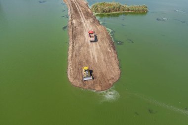 Bulgaristan 'ın Burgaz bölgesinin Meden Rudnik ilçesi yakınlarındaki yeşil sularda yol yapımında çalışan buldozer ve çöp kamyonunun hava manzarası