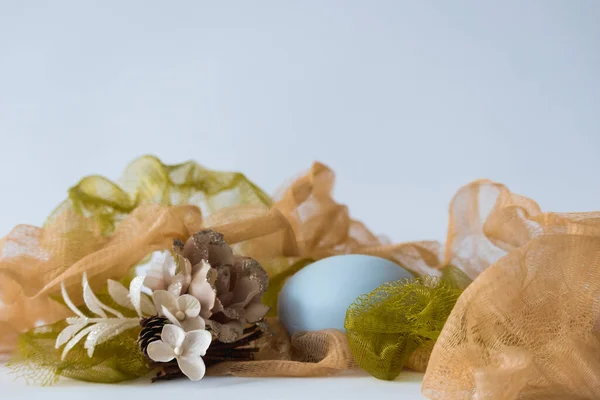 Pastel colored net with flower decoration and blue stone for product placement. Cosmetics background