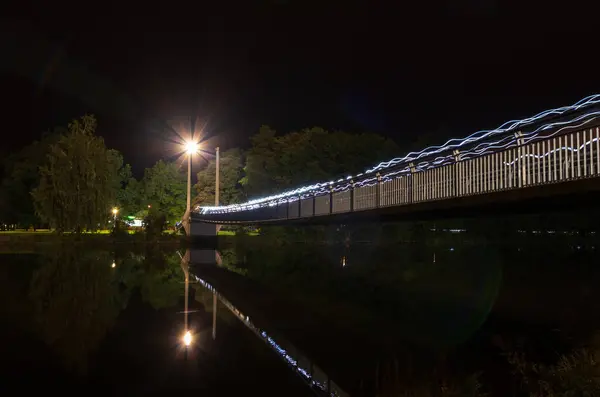 Night run Ceske Budejovice. Long exposure of group race runners running on bridge over river Vltava at night. Trail of headlamp