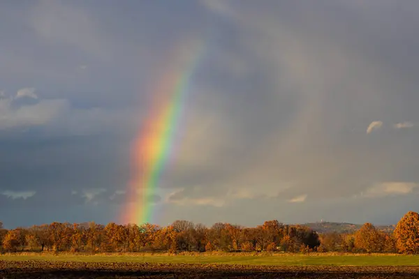 Beauty rainbow in storm cloud above autumn field Czech landscape. Weather, nature background