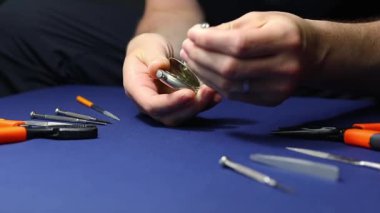 Dostum, saatçi cep saatini cımbız ve tornavidayla onarıyor. Yan çevirme, yavaş çekim. El işi, el yapımı iş arka planı