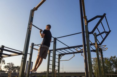 Fitness adamı gün doğumunda oyun parkında barfiks çekiyor. Sabah rutini, zihinsel ve fiziksel güç, sağlıklı yaşam tarzı