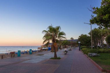 Gün batımında Alanya 'daki plajda palmiye ağacı ve büfeyle yürüyüş, Türkiye 