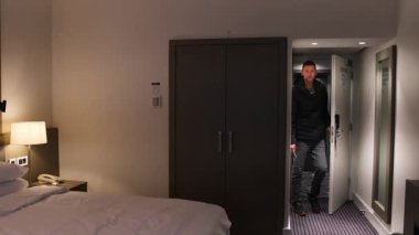 Adamın biri sırt çantasıyla otel odasına giriyor. Seyahat, konaklama geçmişi