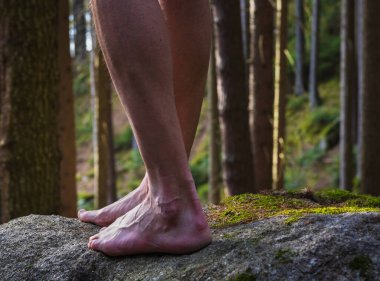 Çıplak ayaklı bir adam ormanda, dikiz aynasından taşın üzerinde yürüyor. Zihinsel, sağlıklı bir yaşam tarzı, yalınayak dolaşma günü