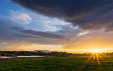 Dramatik günbatımı gökyüzü altında gölet ve tepe Klet ile çayır manzarası. Çek doğası geçmişi