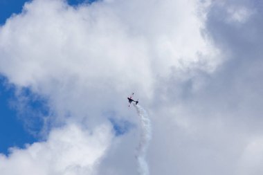Aerobatik bir uçak bulutlu gökyüzünde dumanlı bir manevra yapar.