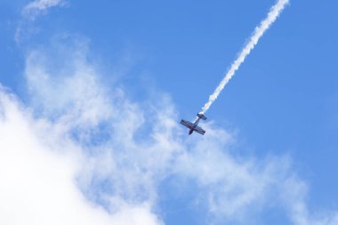 Aerobatik bir uçak bulutlu gökyüzünde dumanlı bir manevra yapar.