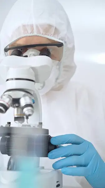 stock image Scientist in ppe analyzing samples and analyzing samples with a microscope in a laboratory setting.