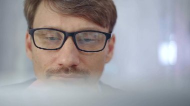 Gözlüklü bir işadamı, yarı saydam bir dizüstü bilgisayar yüzeyi tarafından dikkatle gizleniyor. İş konsepti.