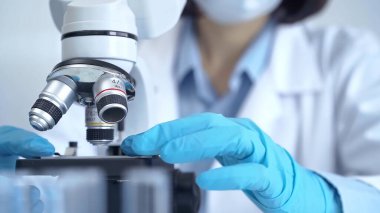 Laboratuvarda mikroskop kullanan bir bilim adamı. Bir laboratuvar ortamında modern bir mikroskobu ayarlayan bir araştırmacının elleri..