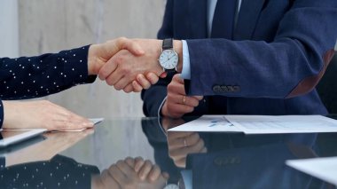 Professional handshake between two professionals and applauds at a corporate meeting with reflection on table over a business meeting. Business people concept. clipart