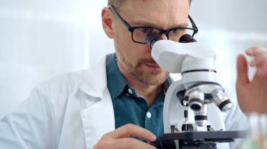 Koruyucu gözlüklü bilim adamı laboratuvarda mikroskop kullanıyor. Mikrobiyoloji bilim konsepti.