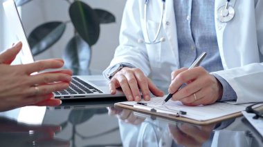 Doktor, cam masaya hasta danışırken bir şeyler yazıyor. Bir de tıp bürosunda bir not panosu var. Tıp konsepti.