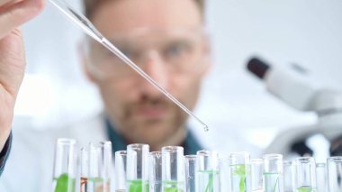 Güvenlik gözlüklü bir araştırmacı laboratuvar borularıyla laboratuvar ekipmanlarına yakın çekim yapıyor. Bilim ve tıp.