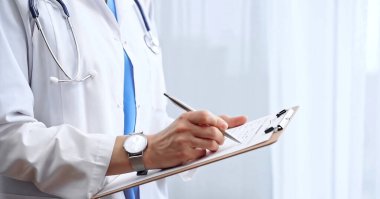 Kadın doktor not defterine not alıyor. Tanımlanamayan bir kadın profesyonel yazının yakın çekimi ve ilaç geçmişi formunu doldurma.