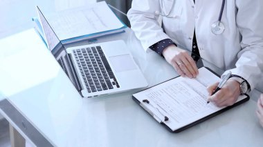 Doktor ve hasta her zamanki sağlık kontrolünden sonra klinikte konuşuyorlar. Kadın doktor not alıyor ve kıdemli bir adamla konuşuyor. Tıp konsepti.