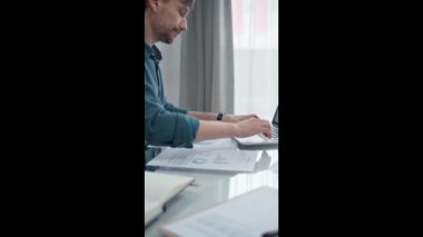 Modern ofiste bilgisayardaki verileri analiz eden bir iş adamı. Yeşil günlük tişört yetişkin erkek profesyonel denetçiye geçiyor. Denetim ve mali analiz kavramı.