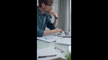 Modern ofiste bilgisayardaki verileri analiz eden bir iş adamı. Yeşil günlük tişört yetişkin erkek profesyonel denetçiye geçiyor. Denetim ve mali analiz kavramı.