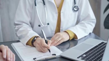 Doktor hastayla evrak işlerini hallediyor. Formları olan doktorların elleri bilgisayara bilgi aktarıyor. İlaç ve sağlık hizmetleri kavramı.