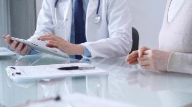 Modern klinikteki hastaya doktor muayenesi. Sağlık bakımı uzmanı elinde tablet bilgisayar olan bir kadınla tıbbi bilgileri tartışıyor. Tıp konsepti.