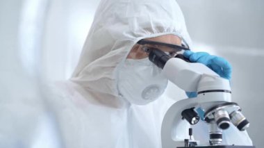 Bir laboratuvar ortamında mikroskop kullanarak örnekleri analiz eden bilim adamı..
