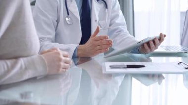 Modern klinikteki hastaya doktor muayenesi. Sağlık bakımı uzmanı elinde tablet bilgisayar olan bir kadınla tıbbi bilgileri tartışıyor. Tıp konsepti.