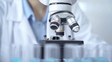 Bir laboratuvar ortamında modern bir mikroskobu ayarlayan bir araştırmacının elleri.