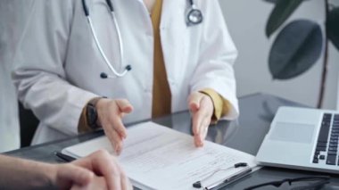 Doktor hastayla konuşuyor. Tıp bürosunda masanın üstünde el kol hareketi yapan bir doktorun yakın çekimi. İlaç ve sağlık hizmetleri kavramı.